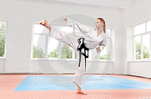 Woman performing martial arts high kick at fight class.