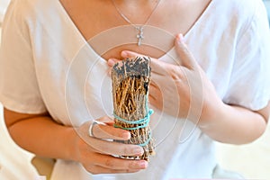 Woman performing ritual of sage burning to cleanse space from negative energy. Self care, physical, mental, emotional, soul.