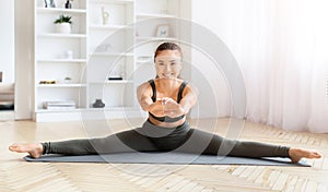 Woman performing a split stretch on yoga mat