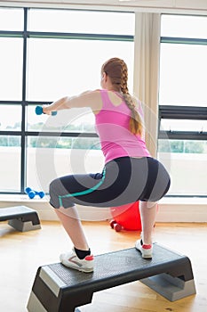 Woman performing step aerobics exercise with dumbbells photo