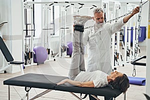 Woman performing a strength training exercise assisted by a kinesiologist