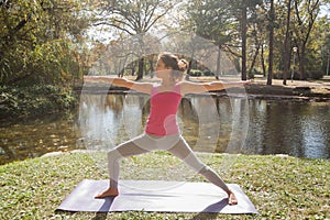 Woman Performing Yoga Exercise In Warrior Pose At The City Park