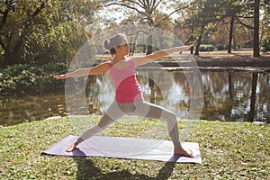 Woman Performing Yoga Exercise In Warrior Pose At The City Park