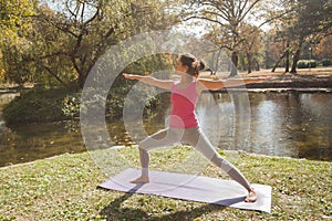 Woman Performing Yoga Exercise In Warrior Pose At The City Park
