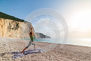 Woman performing yoga exercises on a beautiful empty beach in Greece. Dramatic coastline scenic bay rocky cliffs in the Ionian