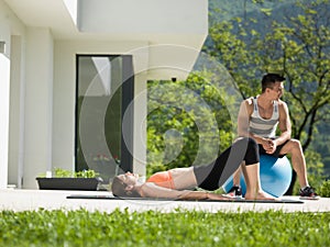 Woman and personal trainer doing exercise with pilates ball