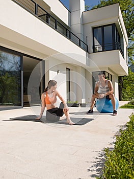 Woman and personal trainer doing exercise with pilates ball