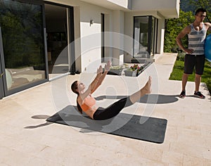 Woman and personal trainer doing exercise with pilates ball