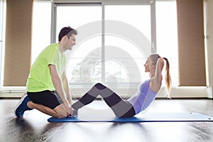 Woman with personal trainer doing sit ups in gym