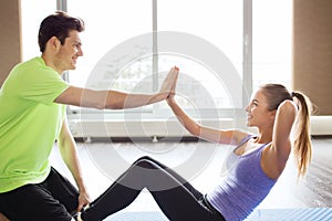 Woman with personal trainer doing sit ups in gym