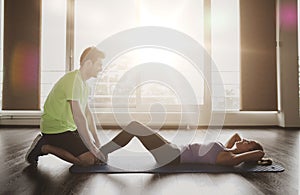 Woman with personal trainer doing sit ups in gym