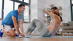 Woman with personal trainer doing sit ups at home