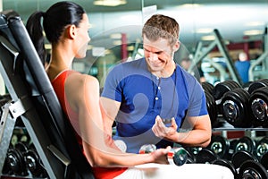 Woman and Personal Trainer in gym with dumbbells