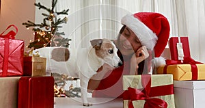 Woman petting dog to santa hat among gifts