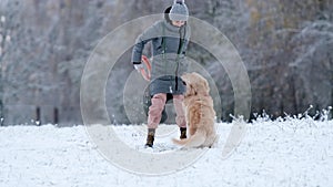 Woman Petting Her Adorable Golden Retriever Dog On A Snow Field