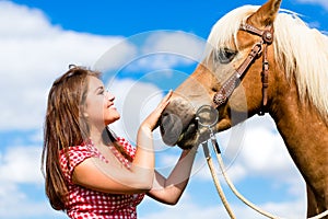 Woman petting horse on pony farm