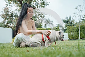 Woman petting pug in sunny garden