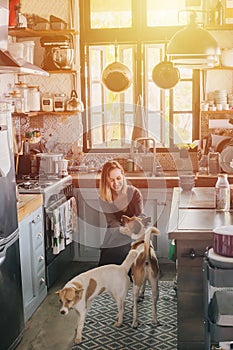 Woman petting two dogs in her old rusty kitchen