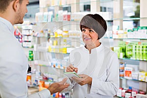 Woman pharmacist helping customers in drug store