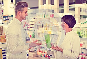 Woman pharmacist helping customers in drug store