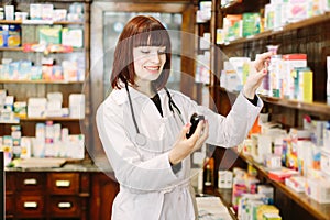 Woman pharmacist holding bottle of medicine in pharmacy or drugstore