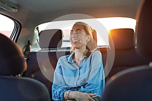 Woman with phone on the back seat of a car