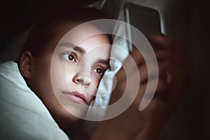 Woman with phone in bed, night