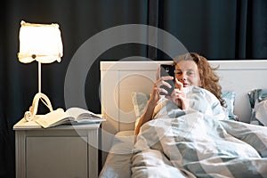 woman with phone in bed night time rest