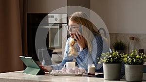 Woman on phone with coffee in kitchen