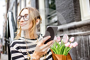 Woman with phone and flowers near the building