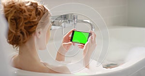 Woman, phone and green screen in bath, mockup and branding space for marketing and advertising. Female, relax and bubble