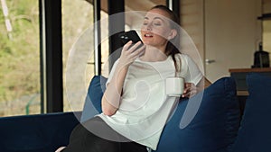 A woman with a phone in her hands speaks on a speakerphone, using a virtual digital voice recognition assistant to