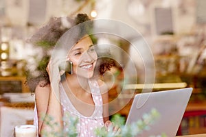 Woman on the phone smiling while in a coffee shop