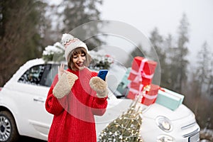 Woman with phone traveling by car decorated for Christmas in mountains