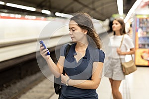 Woman with phone waiting at underground station