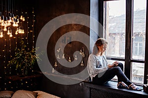 Woman with a phone by the window.