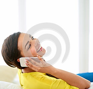 Woman, phonecall and laugh for audio conversation, funny joke and good news on sofa in lounge. Young person, happy and
