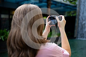 Woman photgrapher holding a digital camera in hands, taking a photo or video