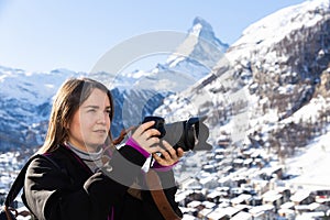 Woman photographer capturing mountain views in Swiss Alps in winter