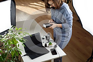 Woman photographer changing batteries in speedlights near her workplace. Freelancer