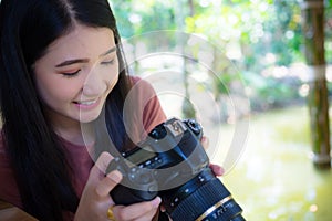 Woman photographer holding dslr camera in hands,  looking at camera.