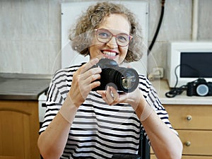 Woman photographer making her blog about photo and video camera in kitchen, lens and flash equipment, woman stocker or freelancer