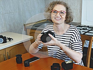 Woman photographer making her blog about photo and video camera in kitchen, lens and flash equipment, woman stocker or freelancer