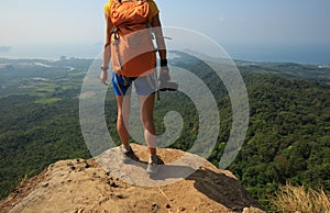 Woman photographer on mountain peak cliff