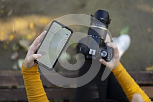 Woman photographer passing her photos from her camera to her mobile phone through Wifi connection