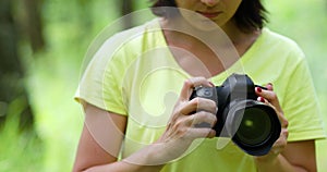 Woman photographer with a photo camera configures outdoor