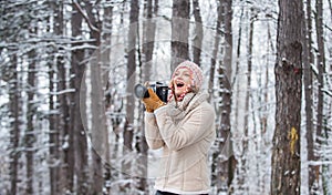 Woman photographer with professional camera. Winter hobby. Enjoy enchanting paleness and freezing atmosphere of winter