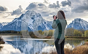 Woman Photographer at River surrounded by Trees and Mountains in American Landscape.