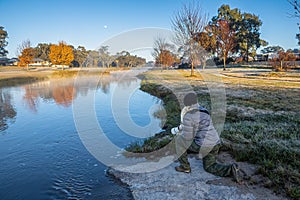 Woman photographer squatting at a pond at sunset