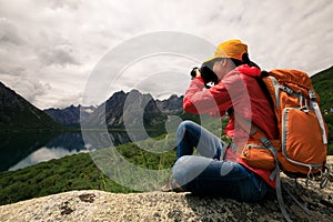 Woman photographer taking photo in mountains